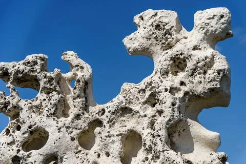 An old stone of complex shape against the background of a blue sky Foto stock