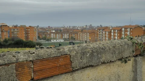 Old stone fence with sharp crashed bottles on the top and city district Stock Footage 94735165