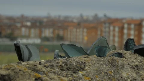 Old stone fence with sharp crashed bottles on the top and city district Stock Footage 94736185