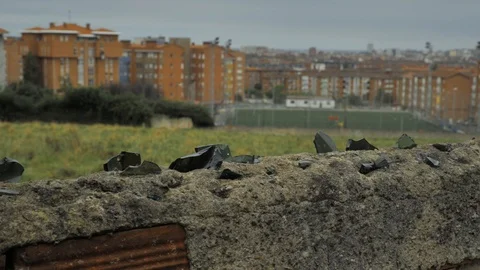 Old stone fence with sharp crashed bottles on the top and city district Stock Footage 94736354