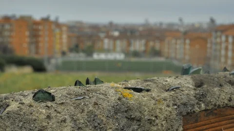 Old stone fence with sharp crashed bottles on the top and city district Stock Footage 94736486