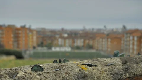 Old stone fence with sharp crashed bottles on the top and city district Stock Footage 94736574