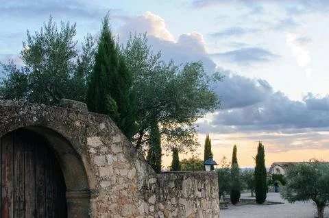 Old stone gate opens to olive grove Stock Photos