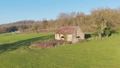 An old stone lavoir with a weathered red roof, set in a green rural landscape Stock Footage 346665685