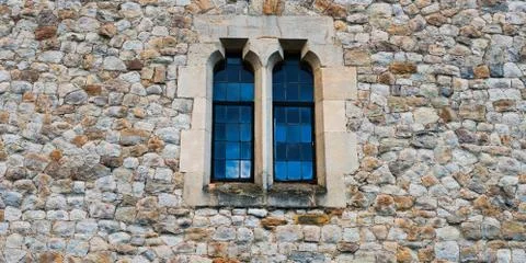 Old stone medieval wall with two windows in center Stock Photos