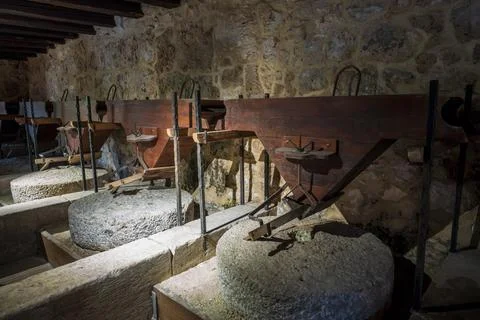 An old stone mill with large grinding wheels and wooden chutes Stock Photos