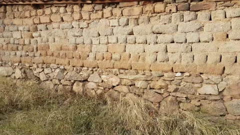 Old stone &amp; mud brick wall, topped with roof tiles Vídeos de archivo 97207139