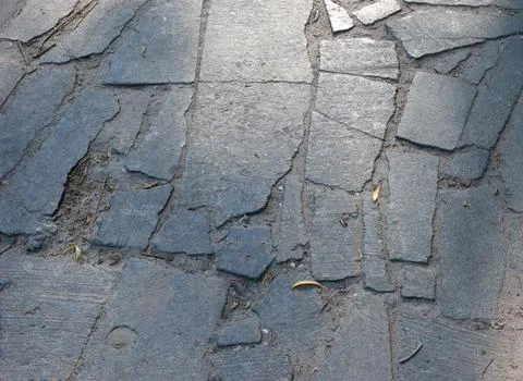 Old stone-paved path made of irregular granite slabs. The surface is uneven.. Stock Photos