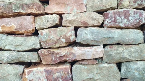 Old stone retaining wall made of irregularly laid blocks of red and pink rock. Stock Footage 233148252