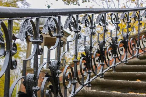 An old stone staircase in a park is bordered by black wrought-iron balustra.. Stock Photos