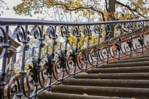 An old stone staircase in a park is bordered by black wrought-iron balustra.. Stock Photos