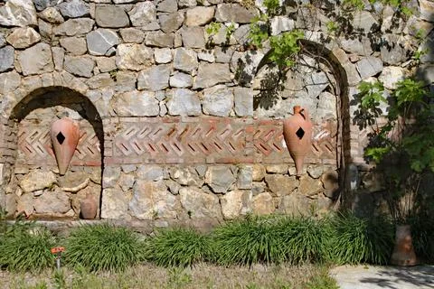 Old stone structure with urns built into a stone wall in the gardens of a res 스톡 사진