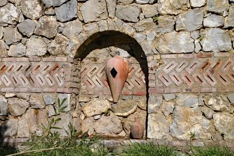 Old stone structure with urns built into a stone wall in the gardens of a res Foto stock