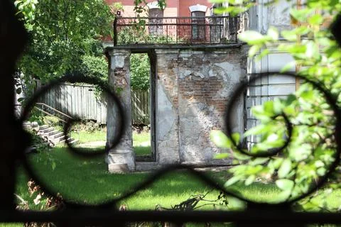 Old stone structure viewed through a fence in a park on a sunny day in summer Stock-Fotos