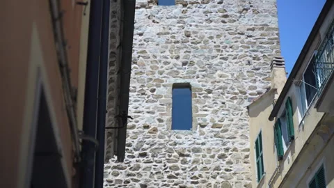 Old stone tower with narrow windows between houses and blue sky Stock Footage 346722580