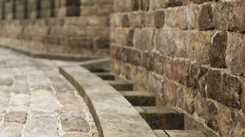 Old stone wall and cobblestone path near a quiet street during the day Stock Footage 344154579