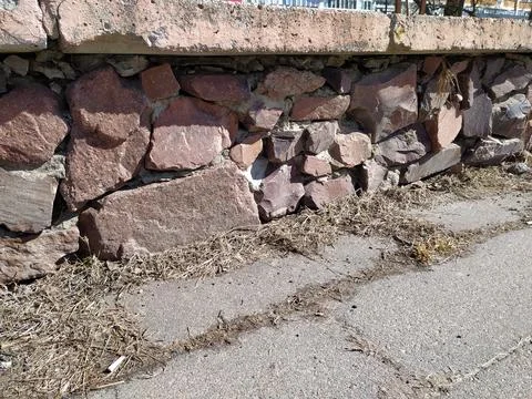 Old stone wall and dry grass on the street. Landscape. Stock Photos
