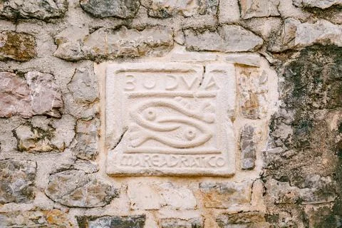 An old stone wall with an applied bas-relief with the inscription BUDVA mare 스톡 사진