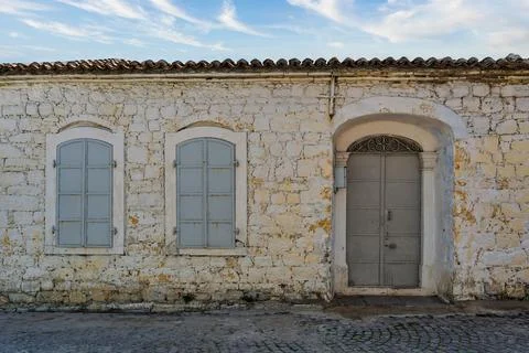 Old stone wall with gray door and windows in sunny location during daytime Stock Photos