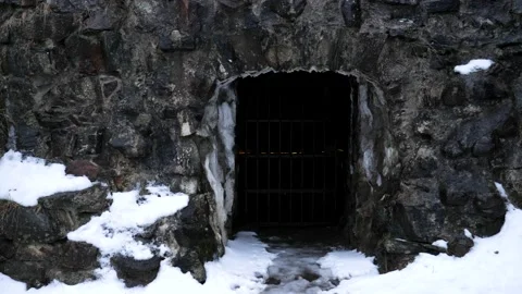 Old stone wall with grid door and melting snow. Video stock 149144464