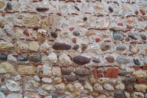 An old stone wall made of pebbles and bricks. Texture. Architecture. Stock Photos