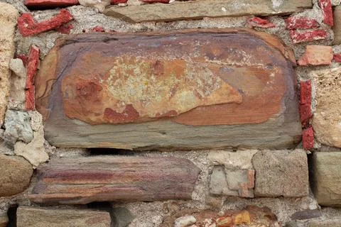 Old stone wall made of various square natural stones in beige, ocher, red and Stock Photos