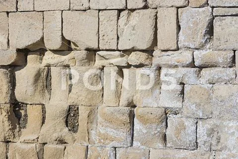 Old stone wall ruined gray uneven ruined hard weathered stone background Stock Photos