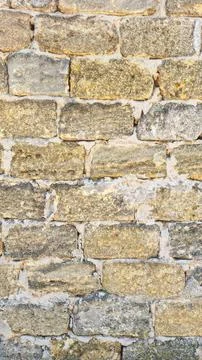 Old stone wall texture with irregular yellow and grey bricks Stock Photos