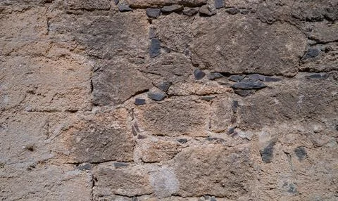 Old stone wall texture with rough blocks and sandy mortar Stock Photos