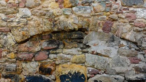 Old Stone Wall With Weathered Textures and Colorful Patches in Historic Setti Foto stock