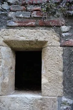 Old stone window frame in a historic brick wall. Stock Photos