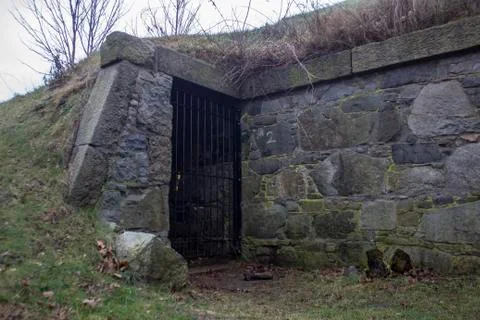 Old structure with gate by stones and hill Stock Photos