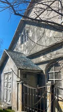 Old structure stands alone in a clear sky surrounded by branches during mid.. Stock Photos