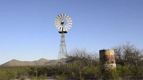 An old style, ancient, desert windmill begins turning in the wind Stock Footage 151117571