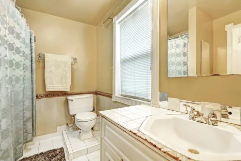 Old style bathroom interior with white tile floor. Has sink, toilet, shower w Stock Photos