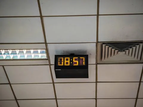Old style electronic watch on the ceiling. Vintage digital clock. Industrial Stock Photos