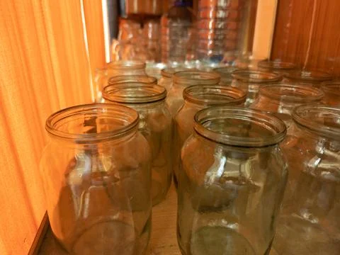 Old style empty glass jars on shelf behind orange curtain Stock Photos
