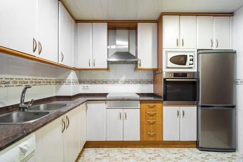 Old style empty kitchen with cabinets, tiled walls, marble countertop and Stock Photos