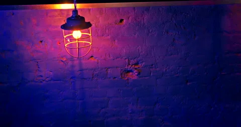 Old style iron loft lantern with yellow electric bulb against blue brick wall Stock Footage 171892473