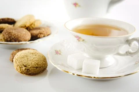 Old-style porcelain kettle with cup of tea with cookies foreground on white b Stock Photos