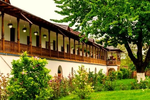 Old style rustic house with laborious wood porch and front green garden tree Stock Photos