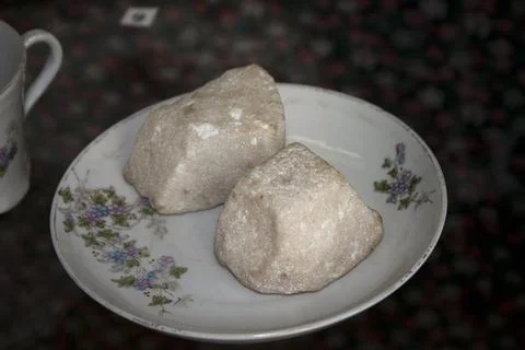 Old sugar on a plate with a cup in the background Stock Photos