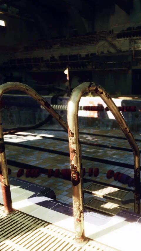 Old swimming pool area with rusted ladder and empty lanes during the day Stock Footage 340282865