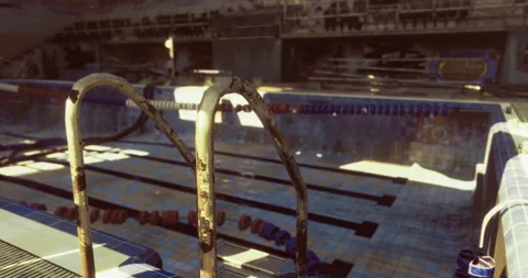 Old swimming pool with rusted ladder and sunlight shining on the tiles Stock Footage 321314408