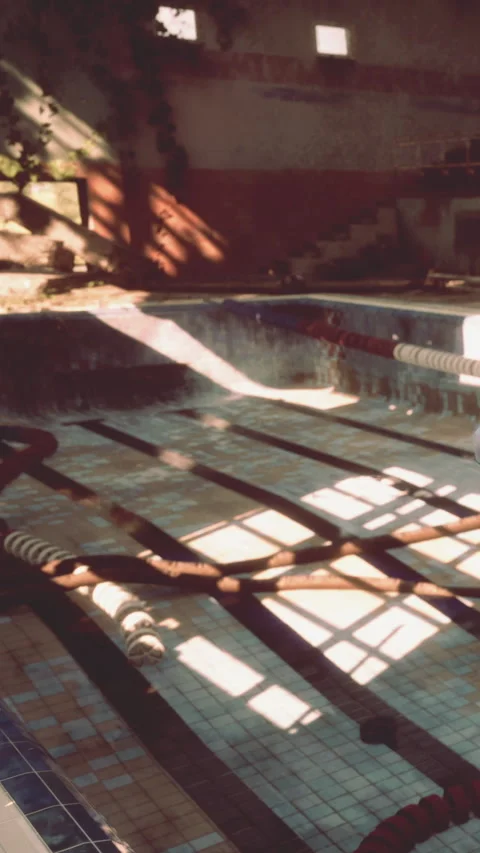 Old swimming pool with sunlight shining through trees during the day Stock Footage 339417767