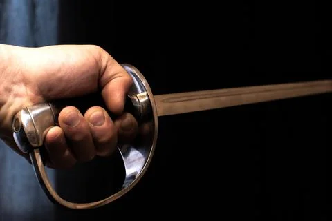Old sword or dagger in man's hand on black background. Stock Photos