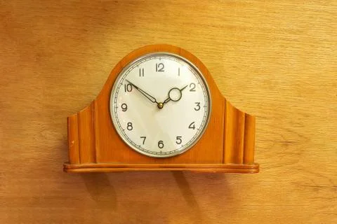 Old table clock made of wood. Mechanical. On a wooden background. Stock Photos