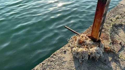 Old tangled rope on the edge of a concrete pier, with a rusty metal post Video stock 336260549