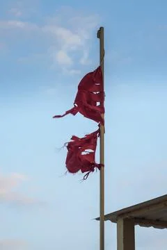 Old tattered red flag in front of the blue sky Stock-Fotos