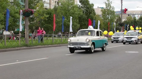 Old taxi car is on the head of procession. Parade is on the Kolpino town streets Stock Footage 41869023